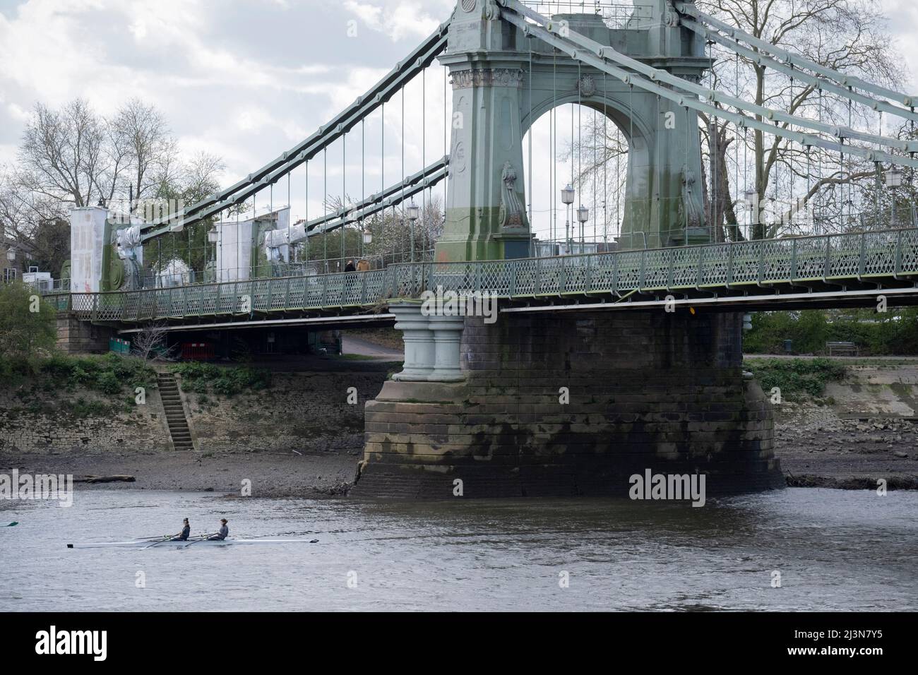 Les rameurs passent sous le pont fermé Hammersmith Bridge tout en s'entraîner sur la Tamise, en passant par les propriétés riveraines près de Barnes, le 6th avril 2022, à Londres, en Angleterre. Les contrôles de sécurité ont révélé des « défauts critiques » et le conseil d'Hammersmith et Fulham a déclaré qu'il n'y avait pas d'autre choix que de fermer le pont vieux de 132 ans jusqu'à ce que les coûts de rénovation puissent être satisfaits. En mars 2022, une nouvelle dépense en capital de 3,5million livres sterling a été approuvée pour faire progresser la conception du concept et les travaux associés visant à stabiliser la structure de grade II. Banque D'Images