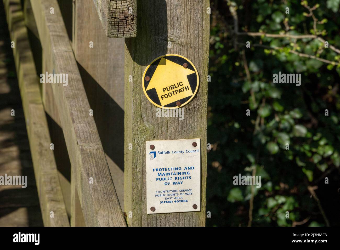 Un poteau en bois faisant partie d'une petite passerelle avec une flèche directionnelle de disque de signe de chemin de pied indiquant tout droit Banque D'Images