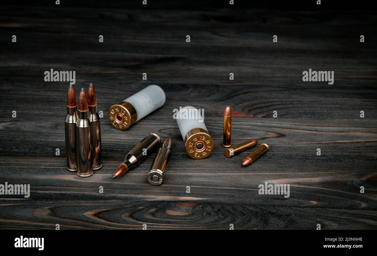Divers types de munitions sur une surface en bois. Cartouches pour armes. Arrière-plan sombre. Banque D'Images