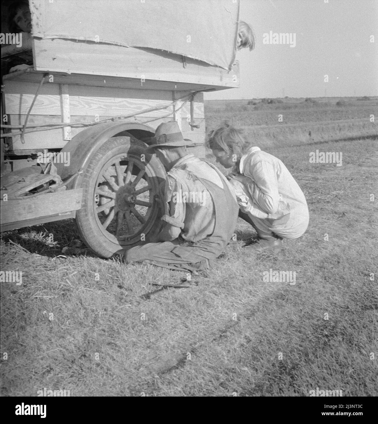 Famille entre Dallas et Austin, Texas. Les gens ont quitté leur maison et leurs connexions dans le sud du Texas, et espèrent atteindre le delta de l'Arkansas pour le travail dans les champs de coton. Personnes sans pénitence. Pas de nourriture et trois gallons de gaz dans le réservoir. Le père tente de réparer un pneu. Trois enfants. Le père dit, "c'est dur, mais la vie est dure de toute façon que vous le prenez". Banque D'Images