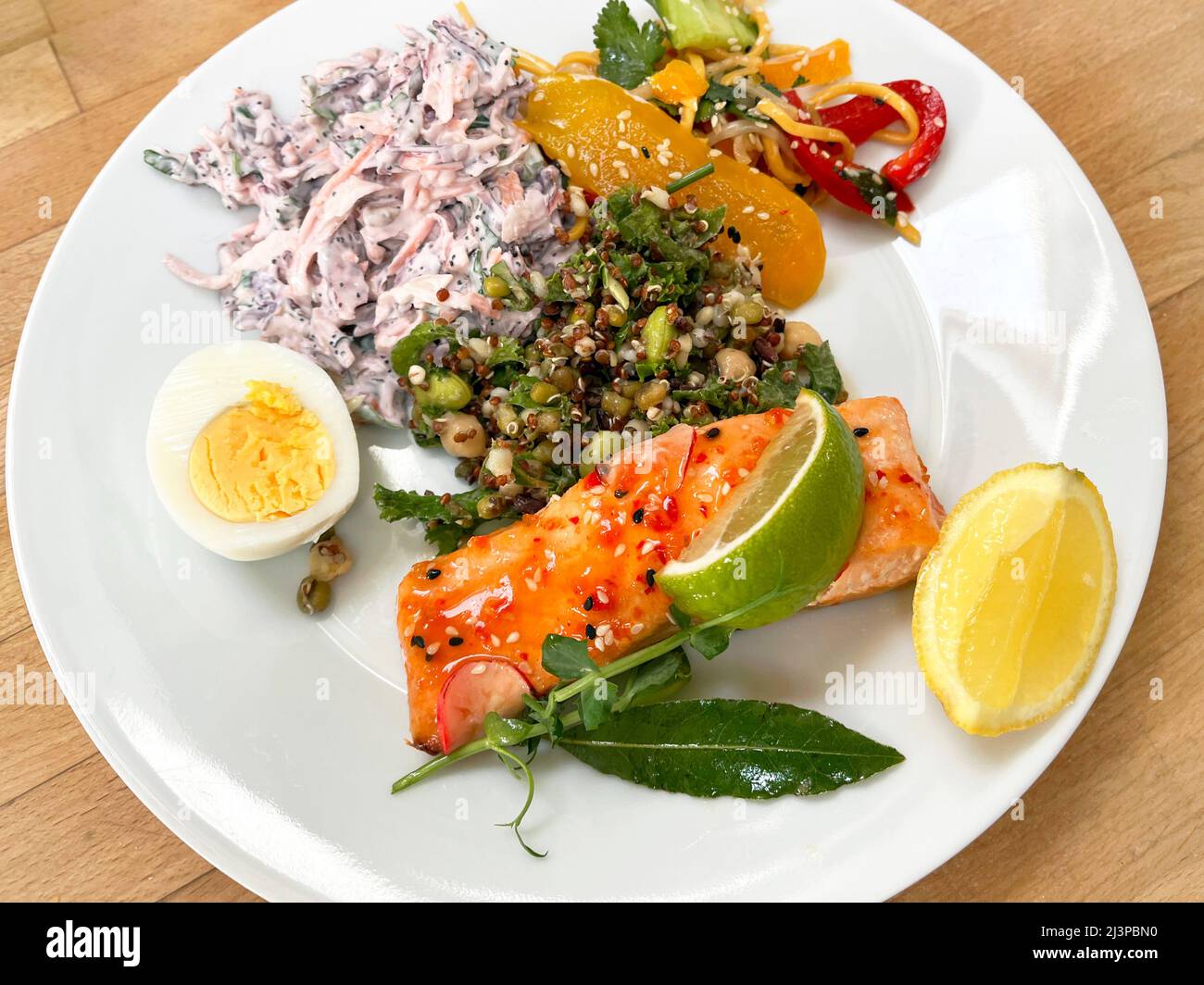 Une assiette de filet de saumon au piment doux et diverses salades. Banque D'Images