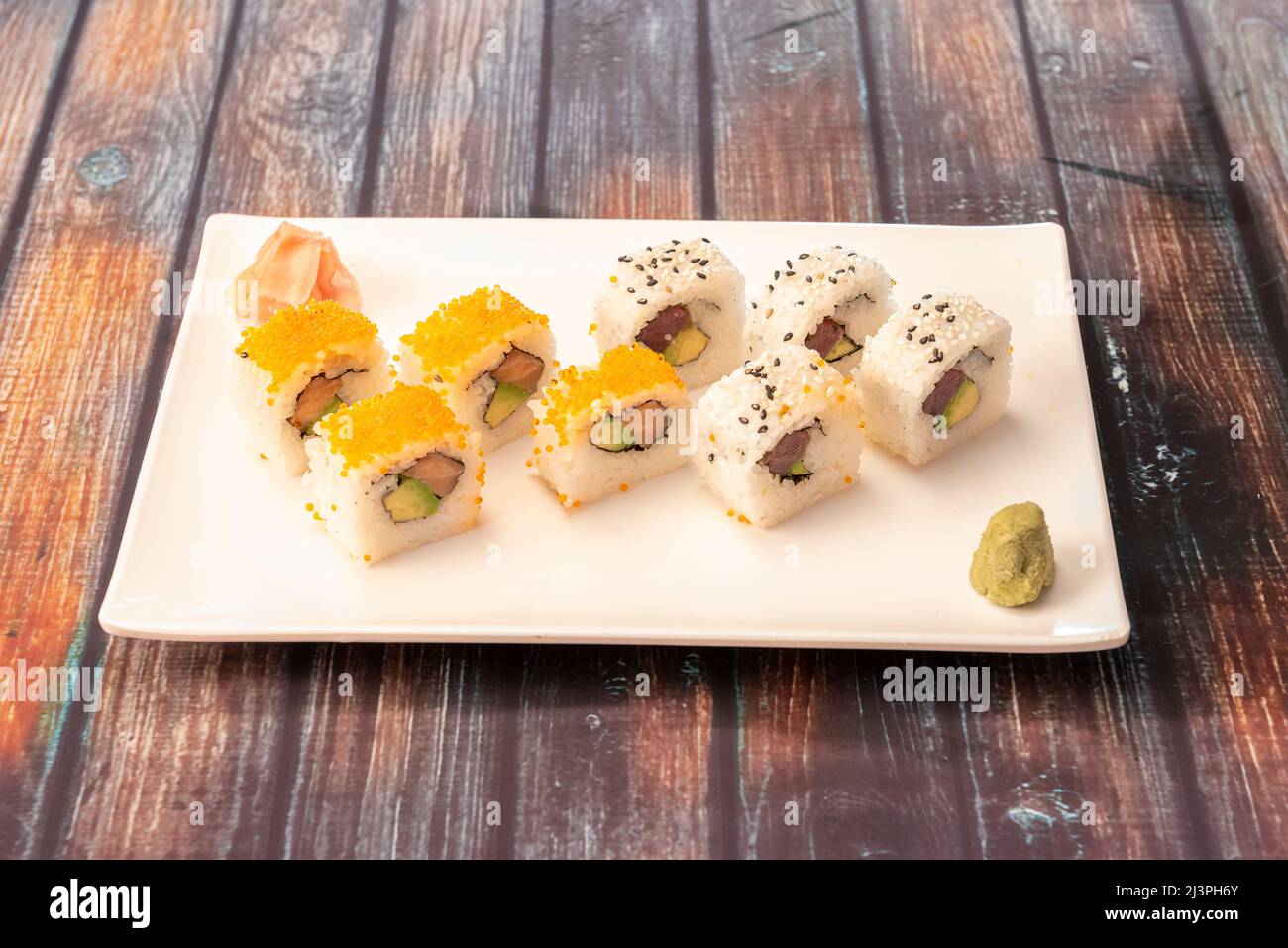 Assortiment de sushis ruramaki california roll avec œufs de macago, thon rouge, saumon norvégien, algues nori, fromage à la crème, avocat mûr, wasabi, gingembre et Banque D'Images