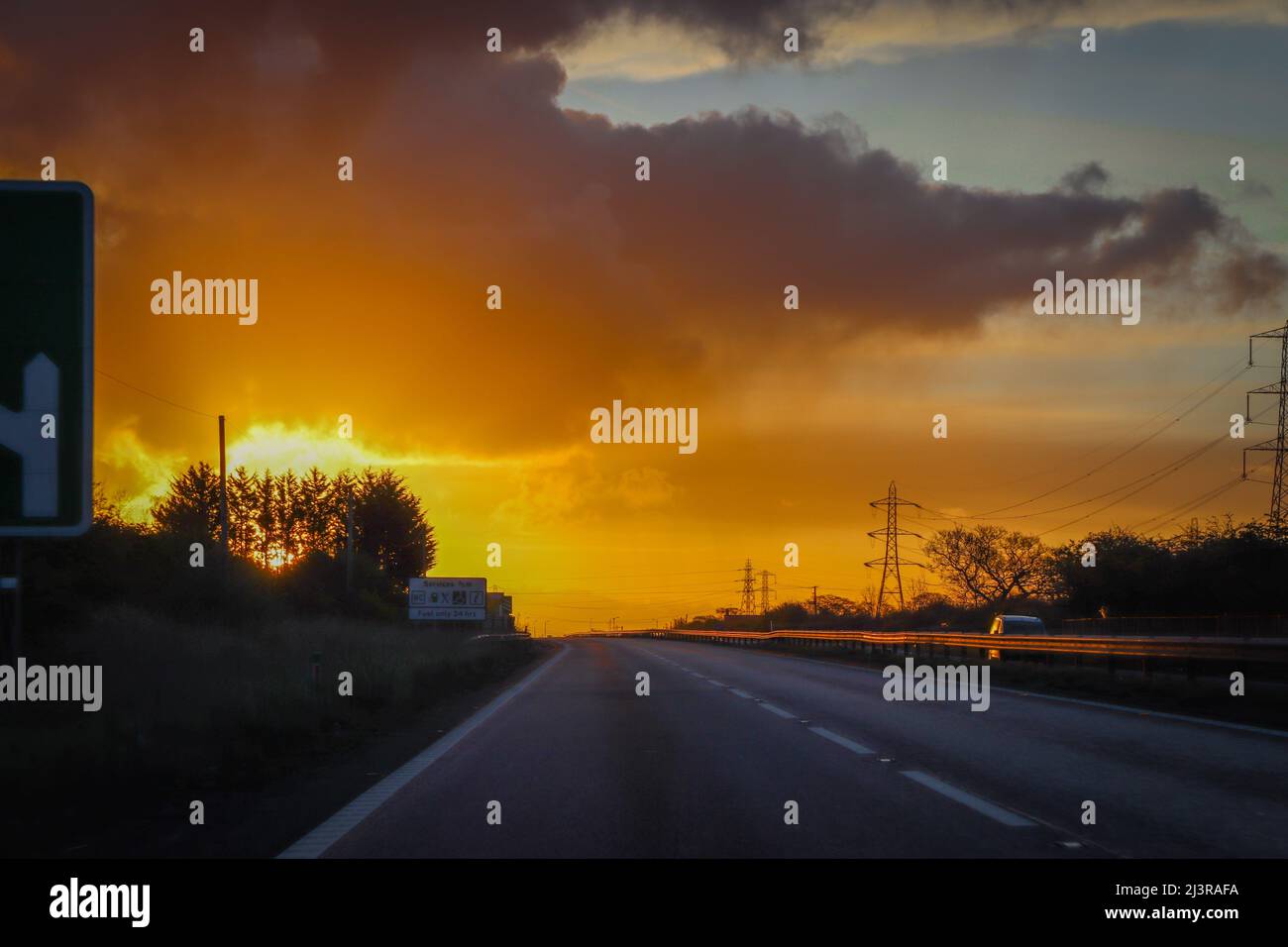 Conduite sur l'autoroute M56 au lever du soleil, route orange Banque D'Images