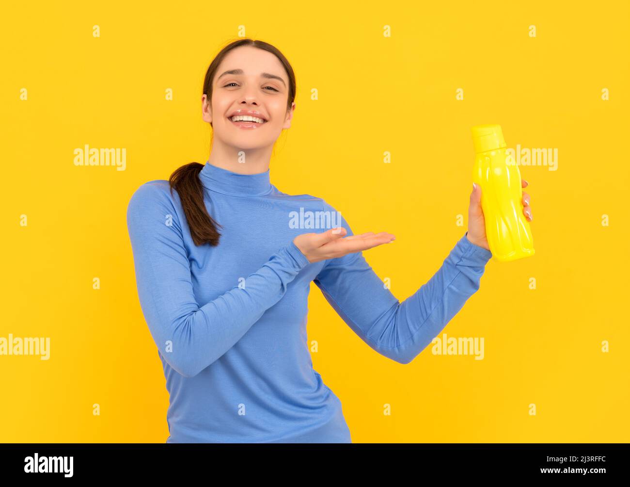 soyez hydratée. femme souriante présentant de l'eau minérale. ayez soif. jeune fille avec une bouteille de sport Banque D'Images