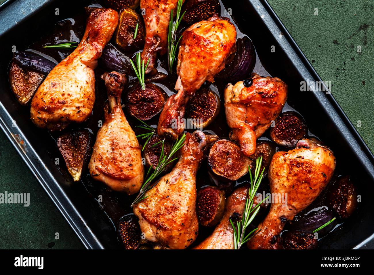 Cuisses de poulet cuites au four, pilons de figues sucrées et oignons en  marinade balsamique sur plaque de cuisson noire, fond de table vert  rouille, vue du dessus Photo Stock - Alamy