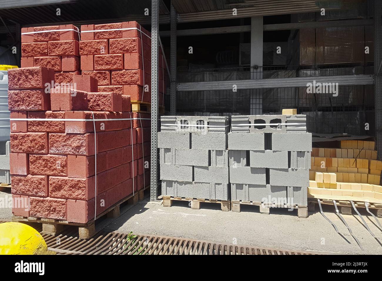 Briques creuses rouges et grises empilées sur des palettes à vendre. Banque D'Images