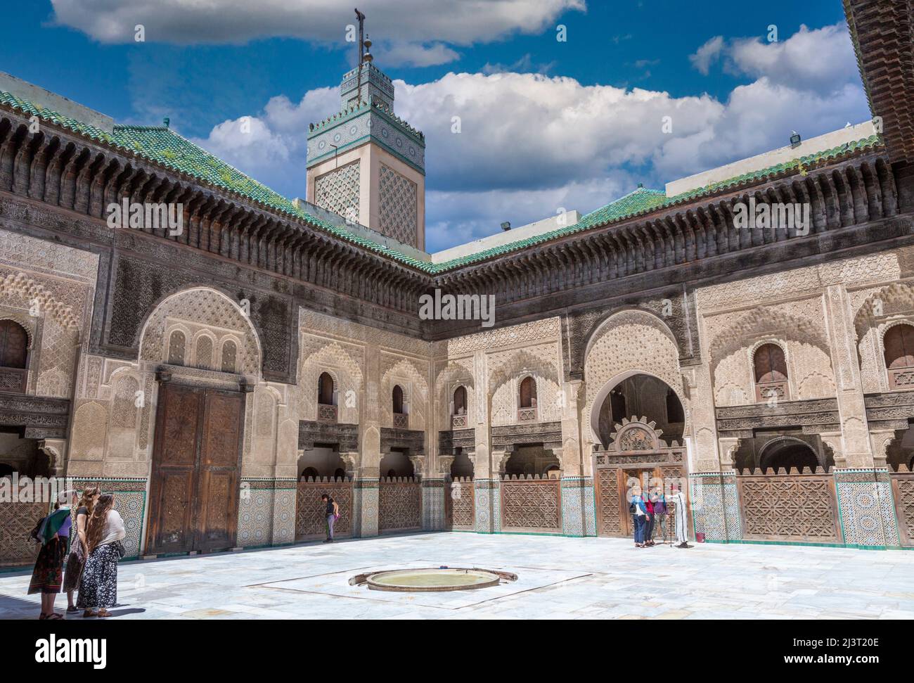 Fes, Maroc. Medersa Bou Inania. Les touristes avec guide dans la cour intérieure. Banque D'Images