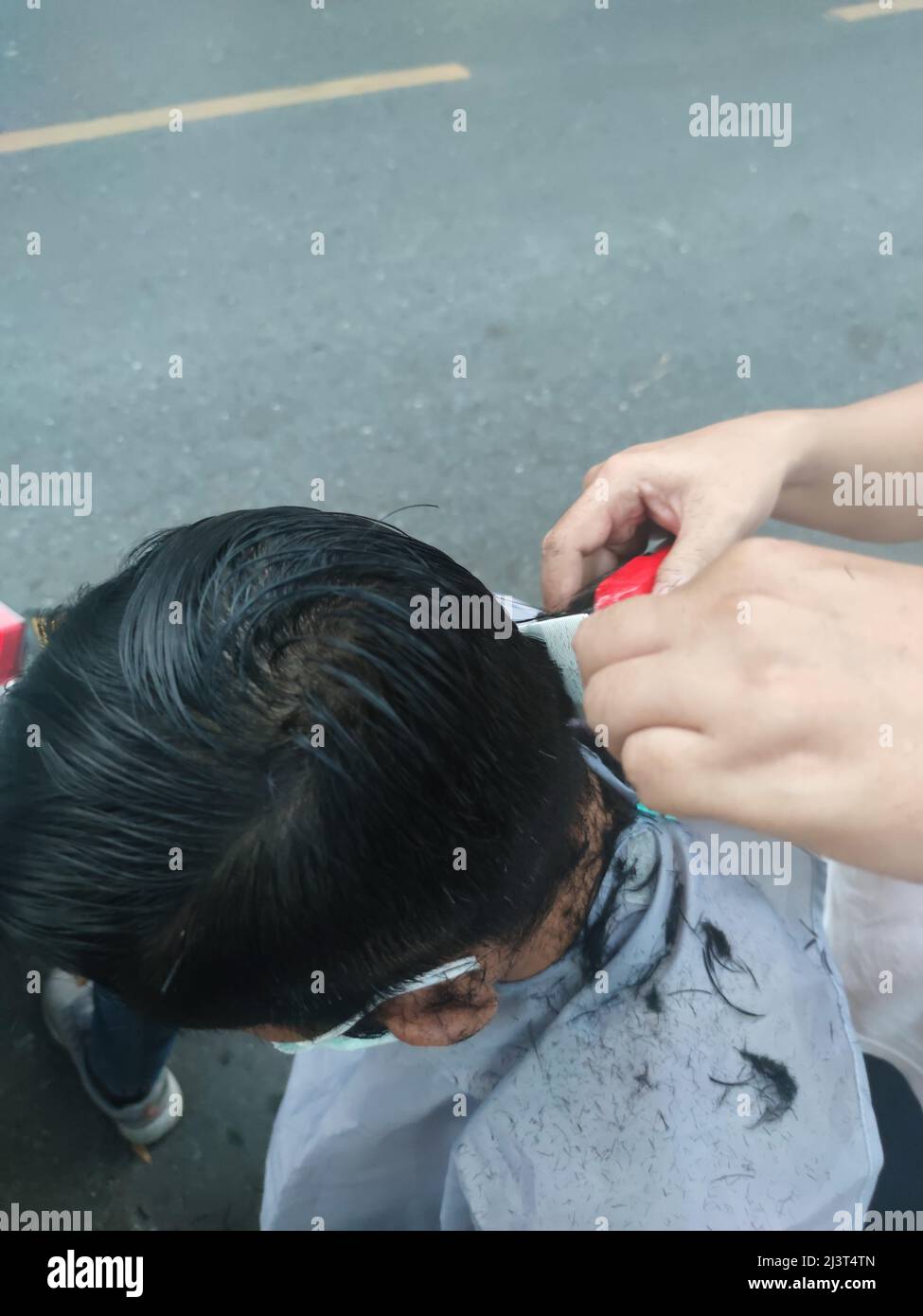 Bangkok, Thaïlande - janvier 22th 2022 : coiffeur de rue coiffant un homme à l'aide de la tondeuse à cheveux Banque D'Images