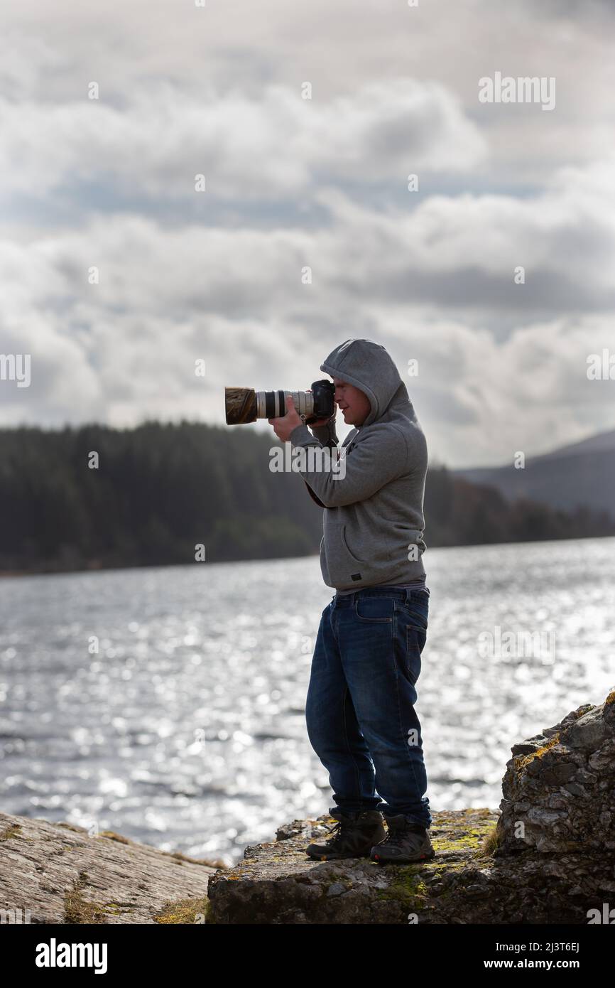 Oliver Hellowell photographe avec la main de syndrome de duvet tenant l'appareil photo au bord d'un Loch écossais Banque D'Images