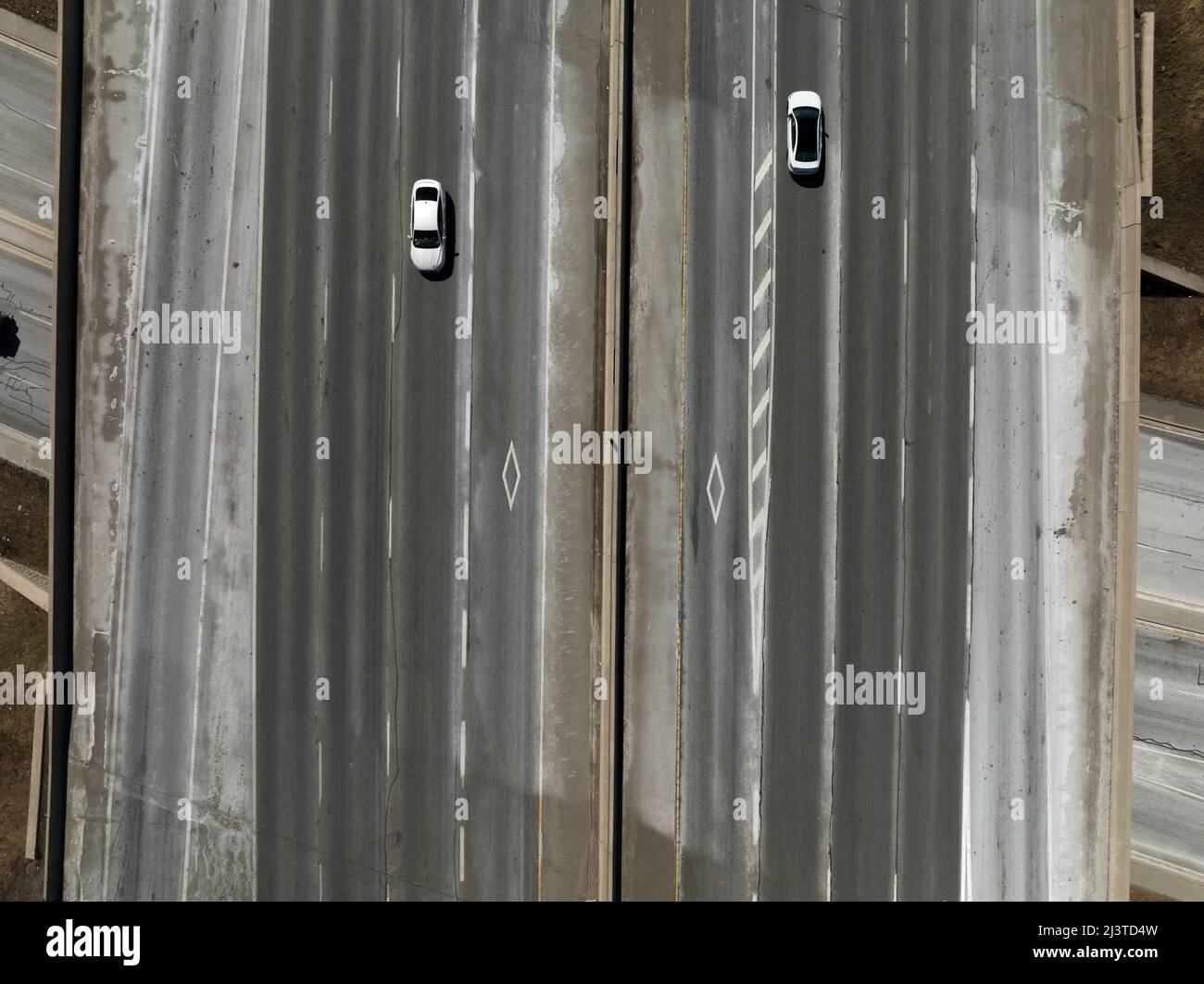 Les logos des voies de circulation sont visibles sur une grande autoroute au fur et à mesure que deux voitures passent. Banque D'Images