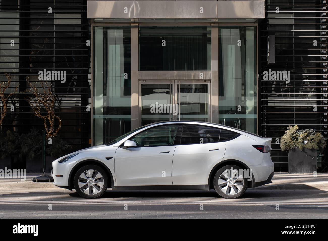 On voit un modèle y blanc de Tesla stationné à l'avant d'un immeuble du centre-ville de Toronto. Banque D'Images