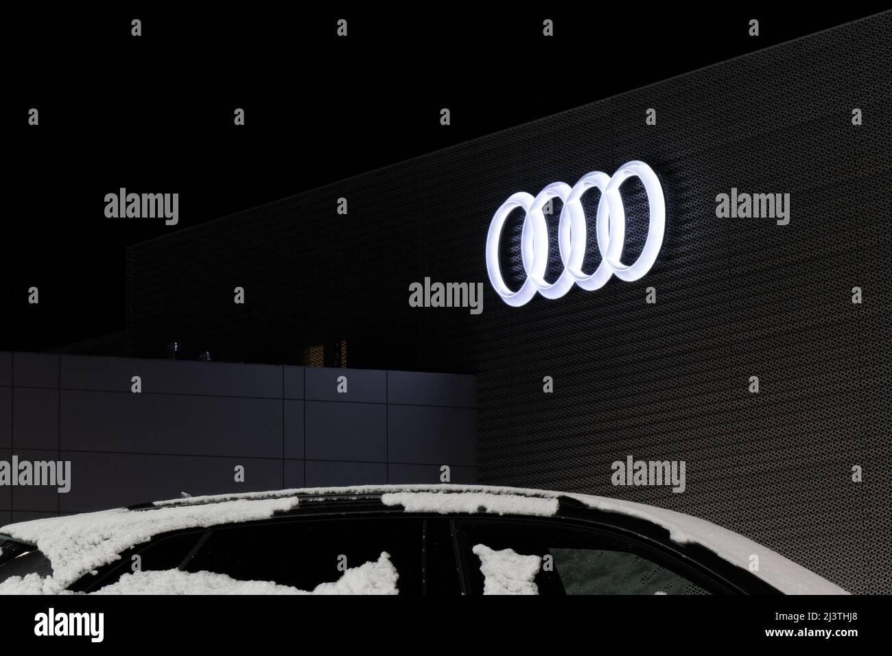 Le célèbre logo Audi à quatre anneaux est illuminé la nuit sur le côté d'un concessionnaire Audi. Banque D'Images