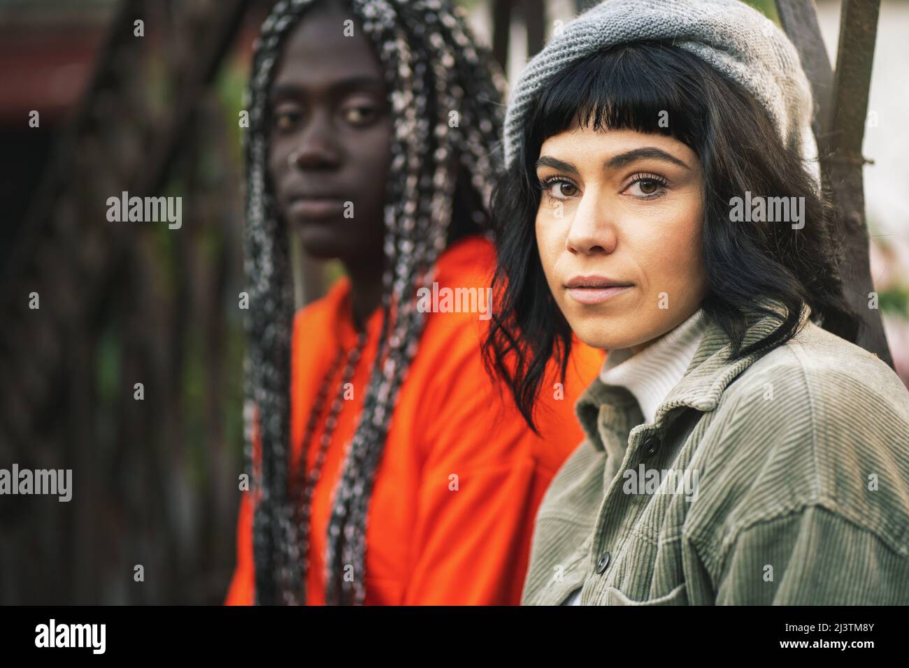 Portrait de deux filles de 20 ans de différentes courses tout en étant assis à l'extérieur, regardant la caméra -. Amitié et intégration concept Banque D'Images