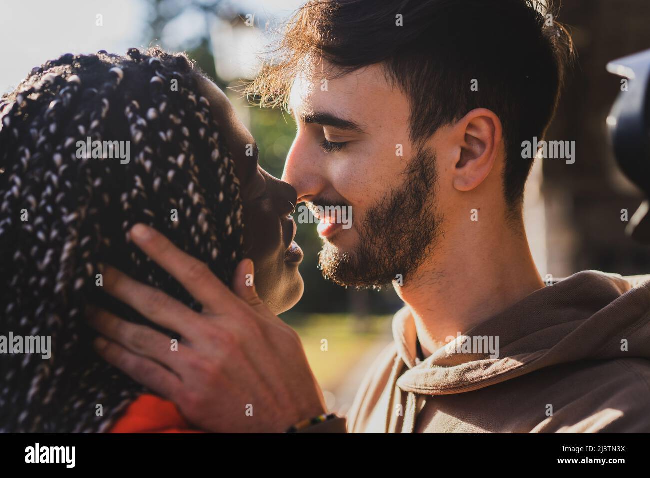 Couple biracial engagé de la génération z jeunes embrassant dans le parc - gros plan Banque D'Images
