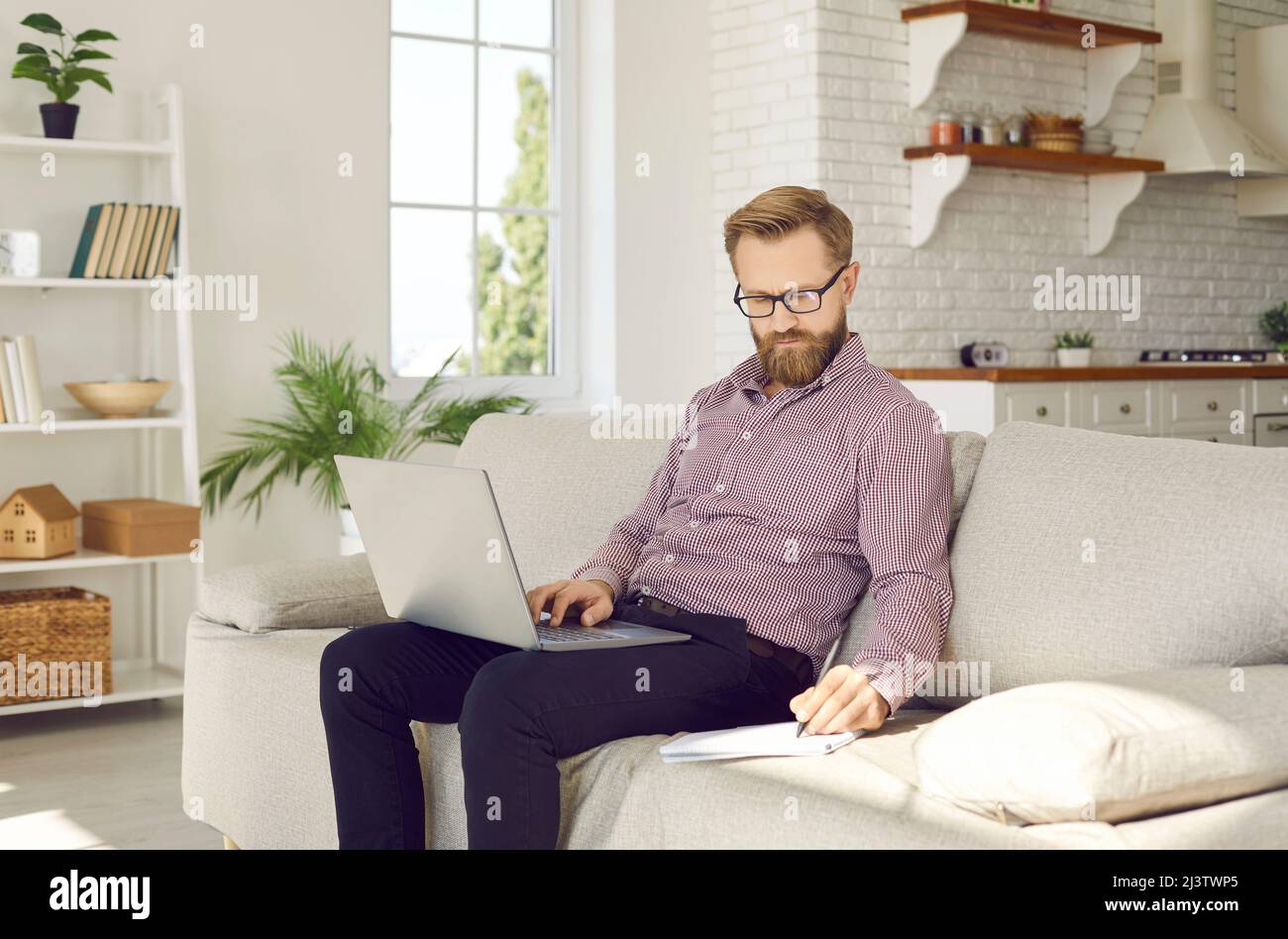 Un homme de race blanche travaille en ligne sur un ordinateur portable à la maison Banque D'Images