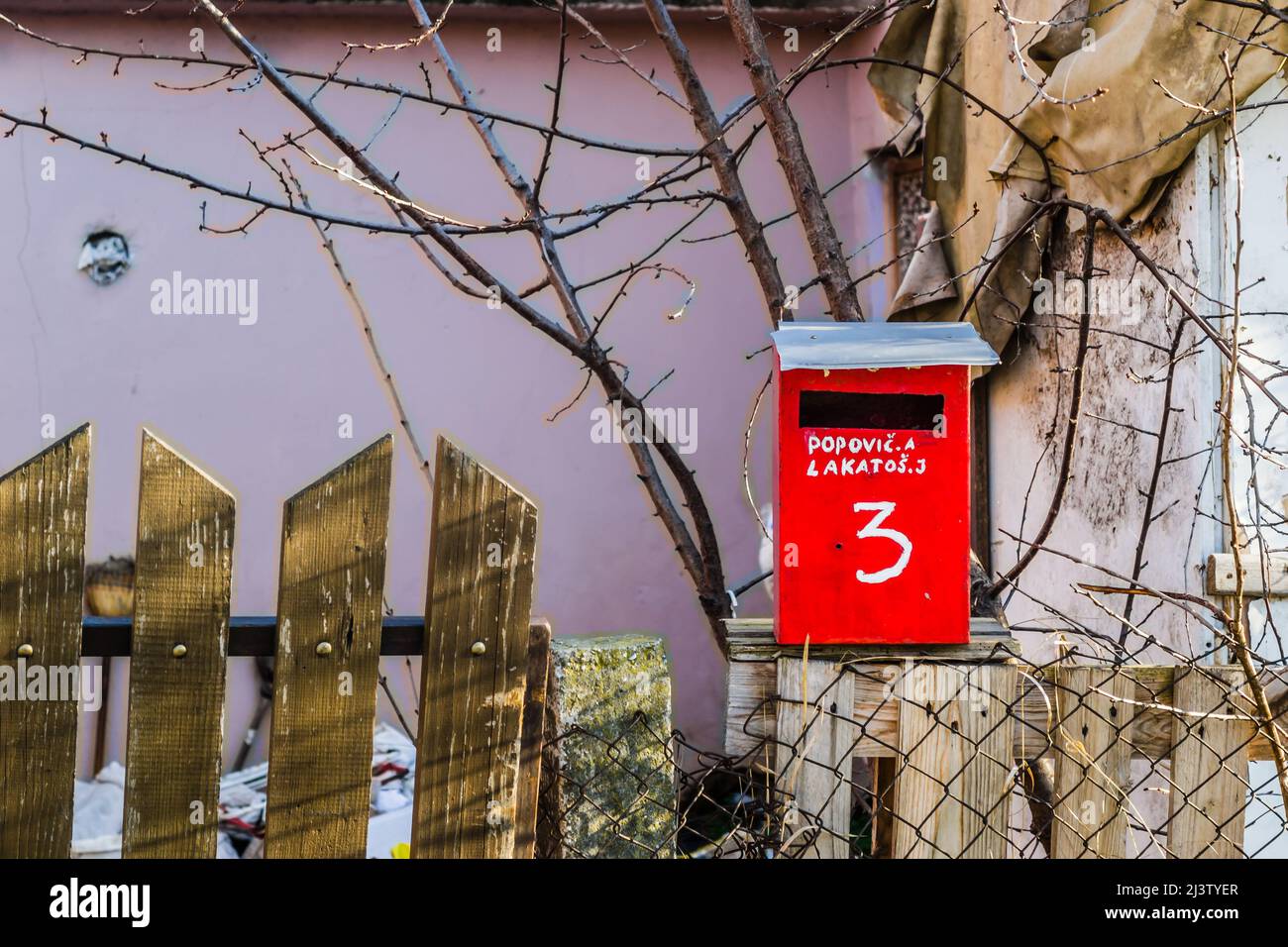 Boîte aux lettres rouge, avec lettres blanches, adresse écrite et numéro de maison sur une clôture en bois. Banque D'Images