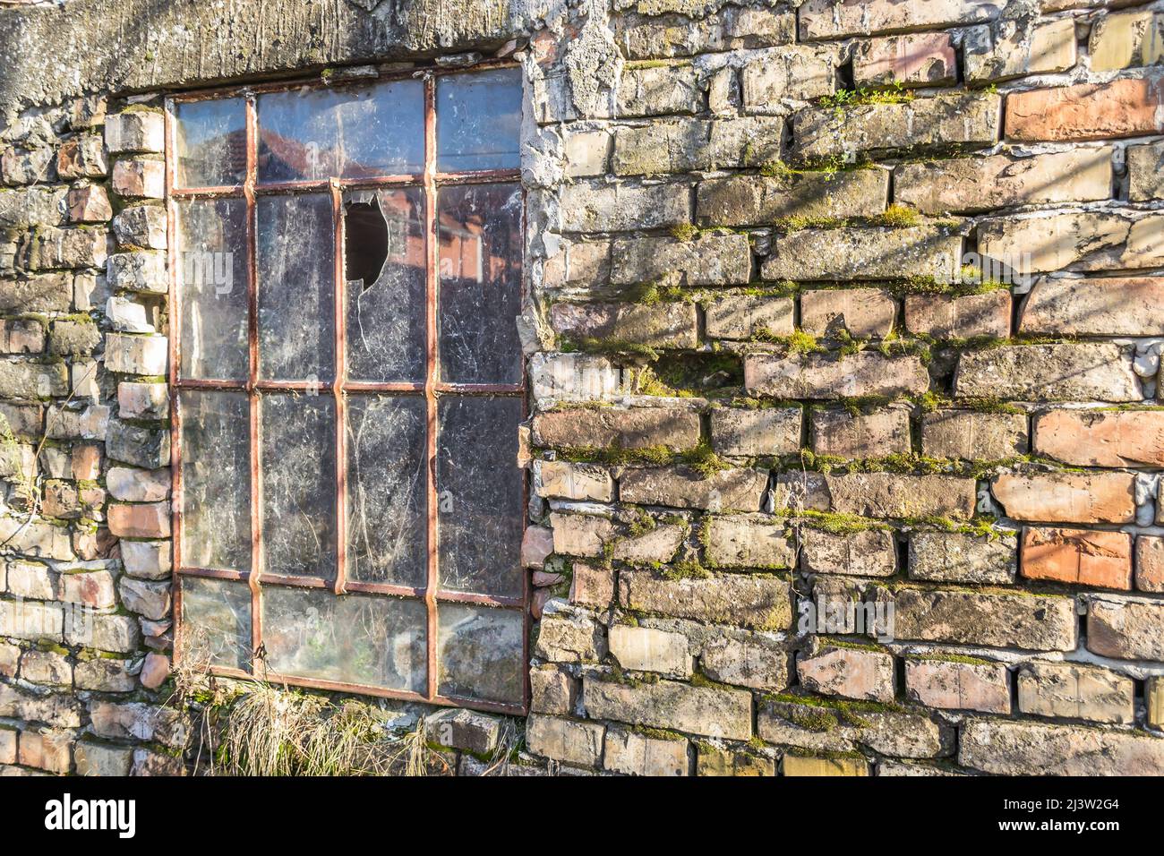 Une vieille fenêtre en métal avec du verre brisé, sur le mur d'une ...