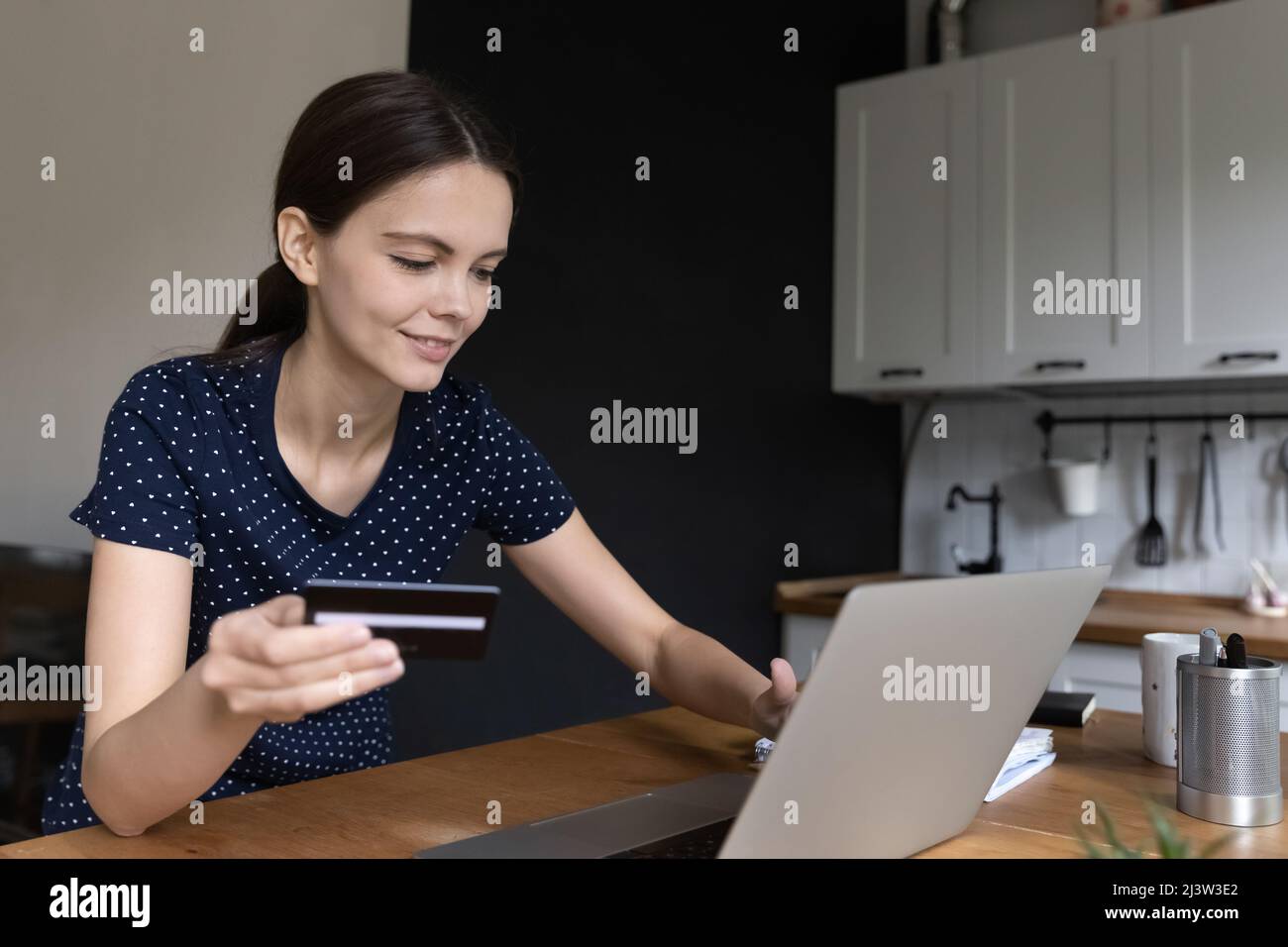 Femme tenant une carte à l'aide d'un ordinateur portable, profitez de vos achats en ligne à la maison Banque D'Images