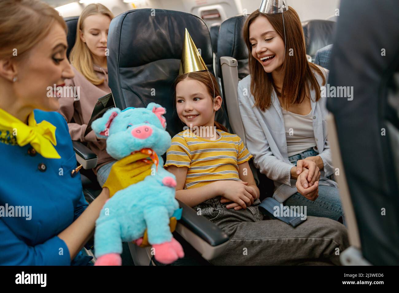Un employé de bord donne le jouet à la fille d'anniversaire dans l'avion Banque D'Images