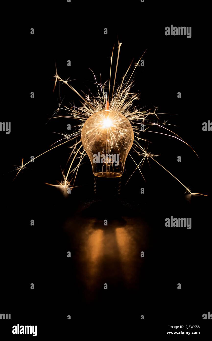 Lampe à incandescence avec étincelles sur fond noir. Banque D'Images
