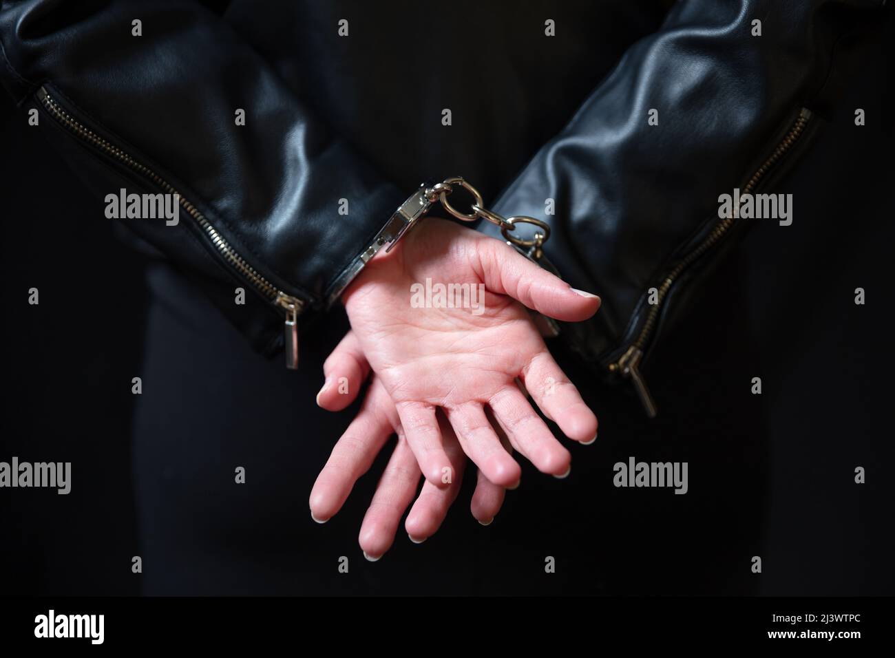 Arrestation, menottée aux mains d'une criminelle. Menottes fermées à l'avant, protection contre la criminalité et la violation de la loi. Banque D'Images