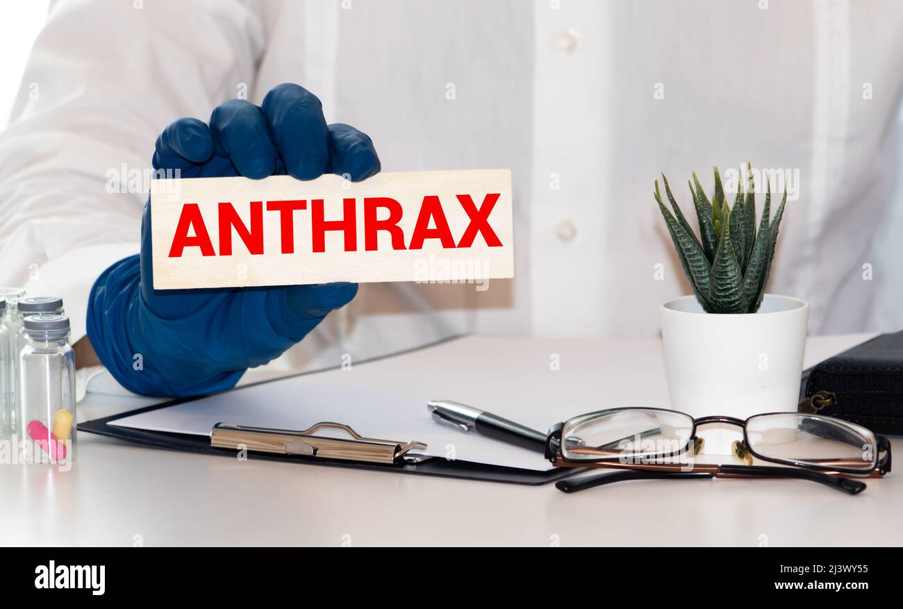 Médecin tenant une carte avec texte ANTHRAX, concept médical. Banque D'Images