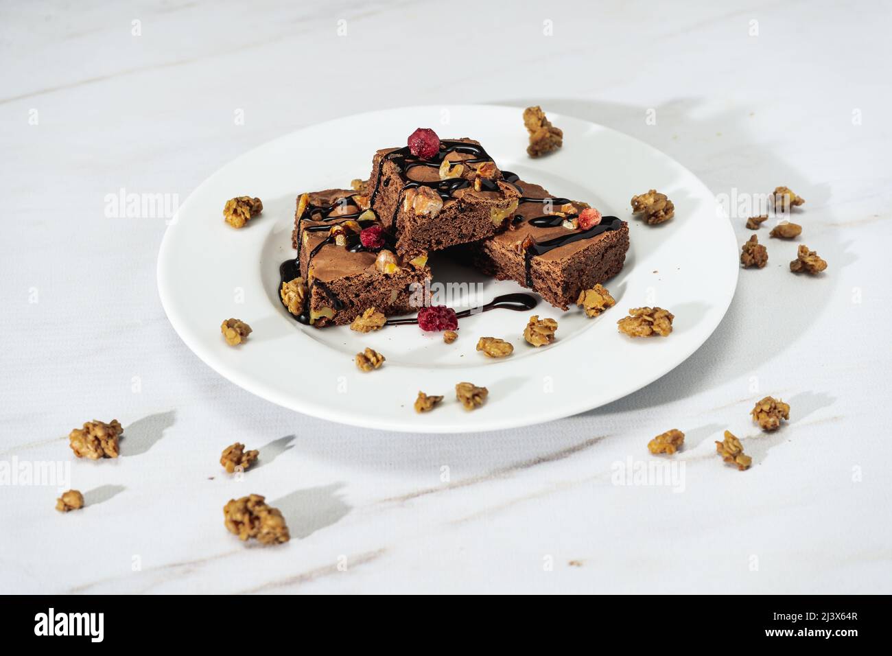 Carrés de brownie au chocolat avec morceaux de noix, fils de chocolat et granola. Concept d'alimentation naturelle et saine. Vue en hauteur. Banque D'Images
