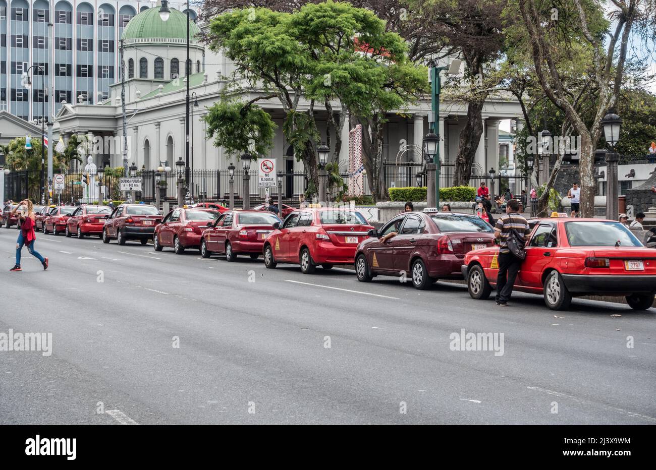 Ligne de taxis rouges avec église catholique en arrière-plan à San Jose, Costa Rica. Banque D'Images