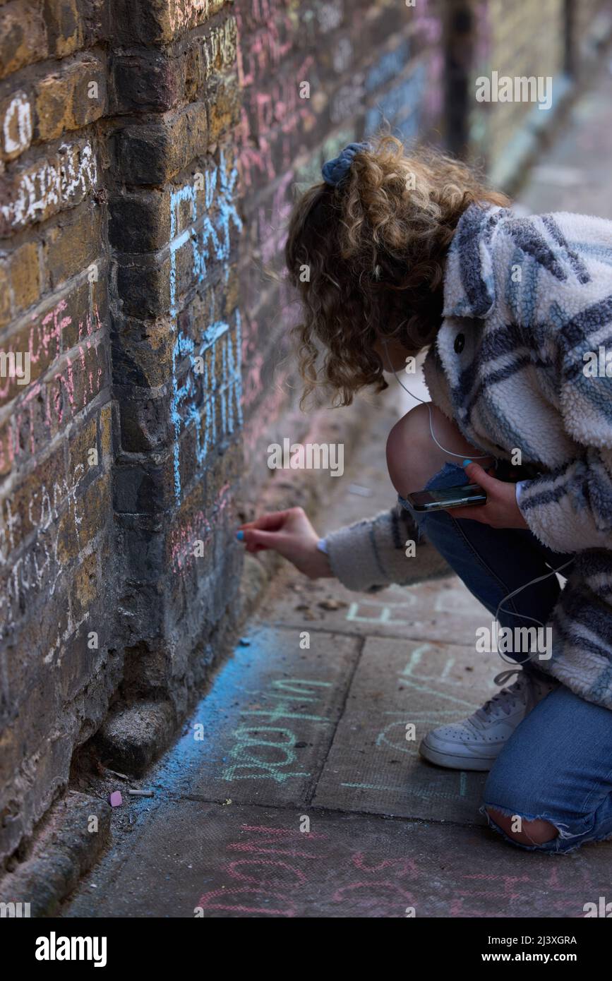 Tenez-vous pour le manifestant de l'Ukraine, Londres près de la fille de l'ambassade russe écrire sur le mur avec de la craie Banque D'Images