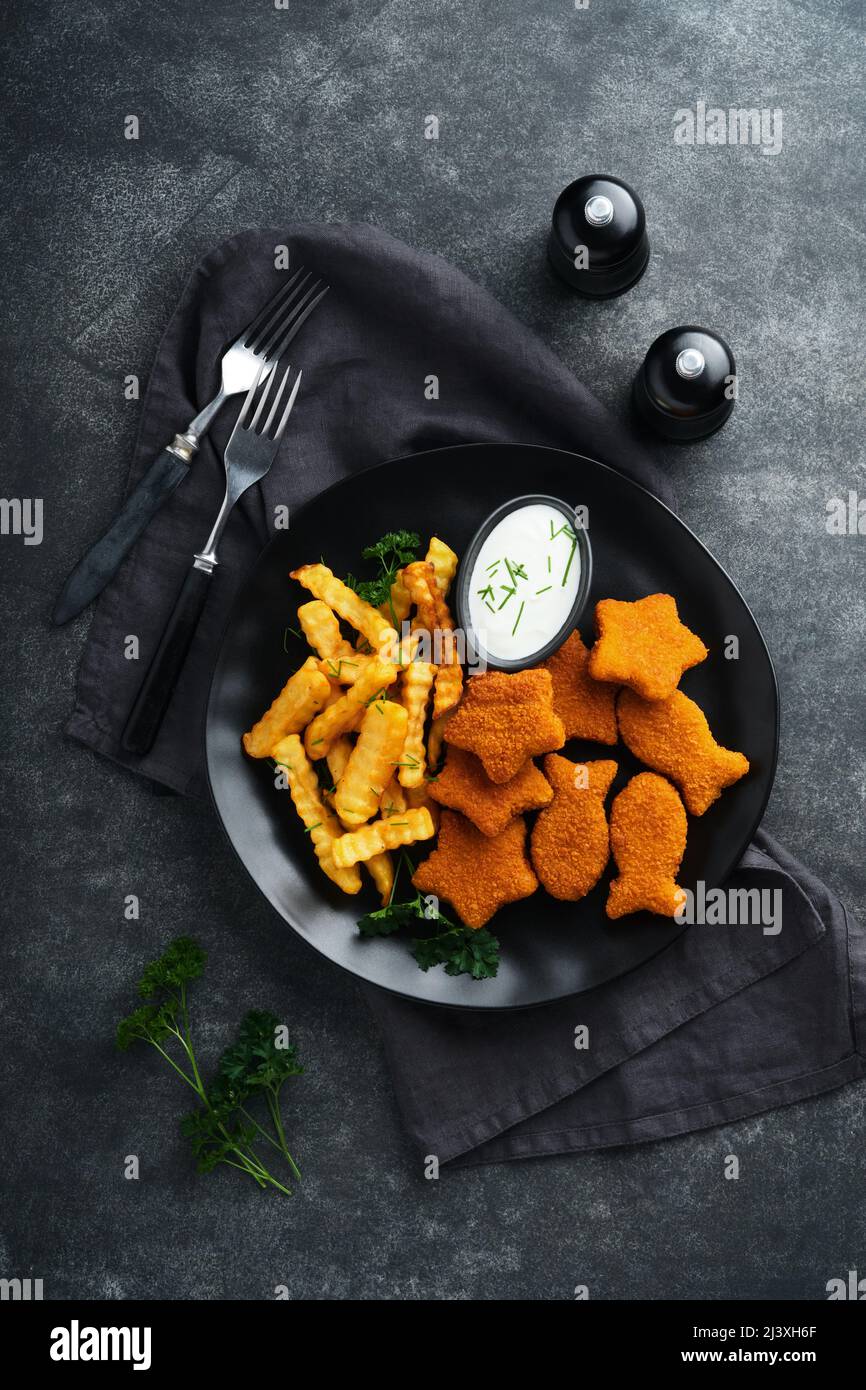 Fish Chips, restauration rapide britannique. Bâtonnets de poisson avec frites sur plaque noire sur fond de table noire. Cuisine traditionnelle britannique authentique ou Banque D'Images