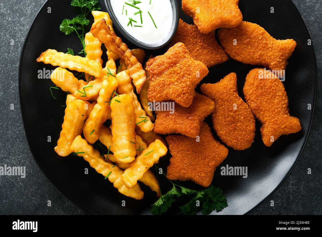 Fish Chips, restauration rapide britannique. Bâtonnets de poisson avec frites sur plaque noire sur fond de table noire. Cuisine traditionnelle britannique authentique ou Banque D'Images