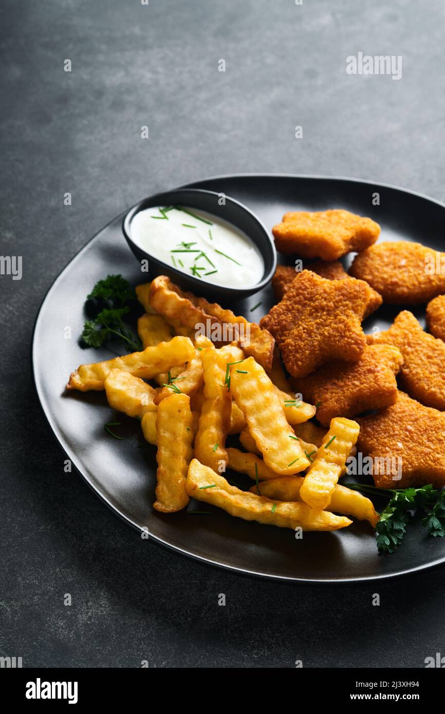 Fish Chips, restauration rapide britannique. Bâtonnets de poisson avec frites sur plaque noire sur fond de table noire. Cuisine traditionnelle britannique authentique ou Banque D'Images