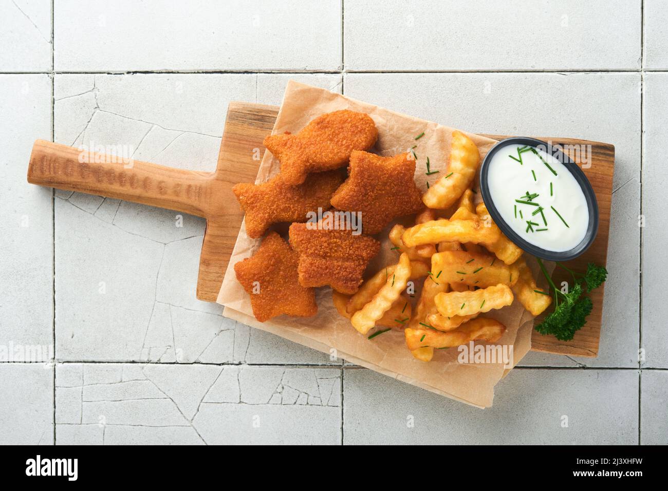 Fish Chips, restauration rapide britannique. Les bâtonnets de poisson aux frites sont fixés sur un panneau rustique, sur un fond de table de comptoir en carreaux gris craquelés. Tradition Banque D'Images