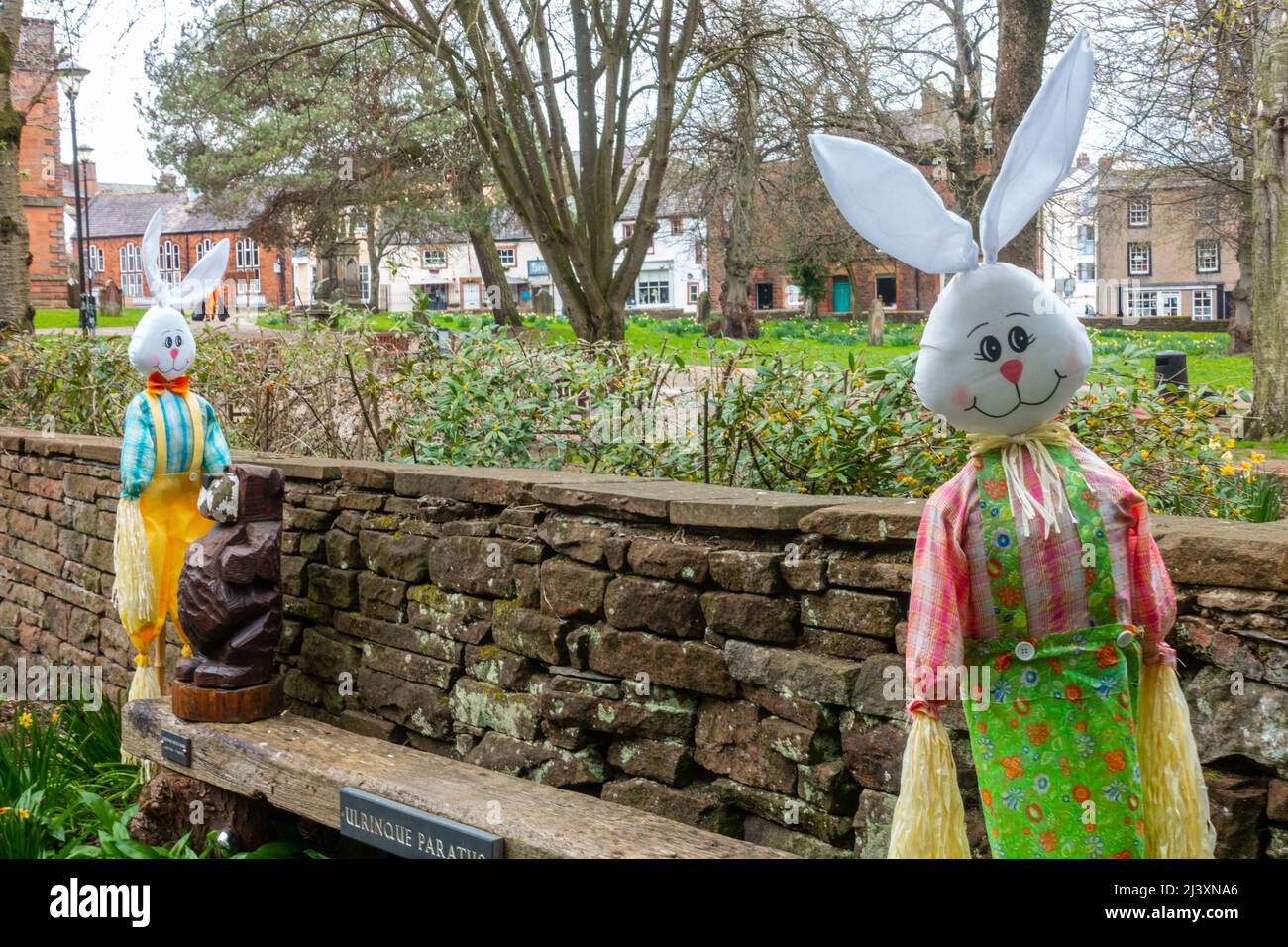 Un couple de jouets en peluche de lapin se trouvent à chaque extrémité d'un banc dans un jardin public à Penrith, Cumbria, Royaume-Uni Banque D'Images