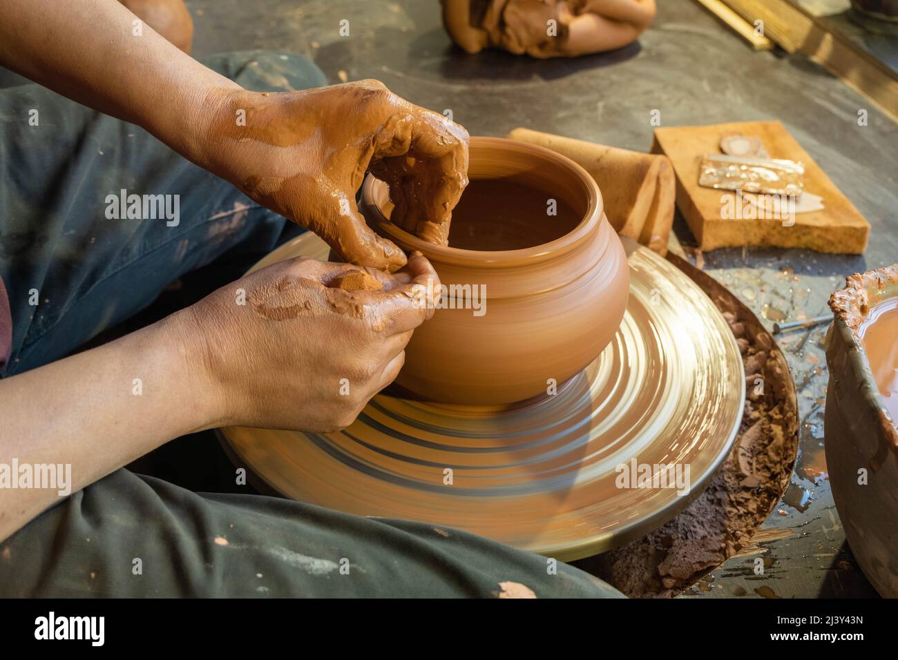 poterie, atelier, concept d'art céramique - gros plan sur les mains masculines sculptez un nouvel ustensile avec des outils et de l'eau, les doigts de l'homme travaillent avec la roue de potier et ra Banque D'Images