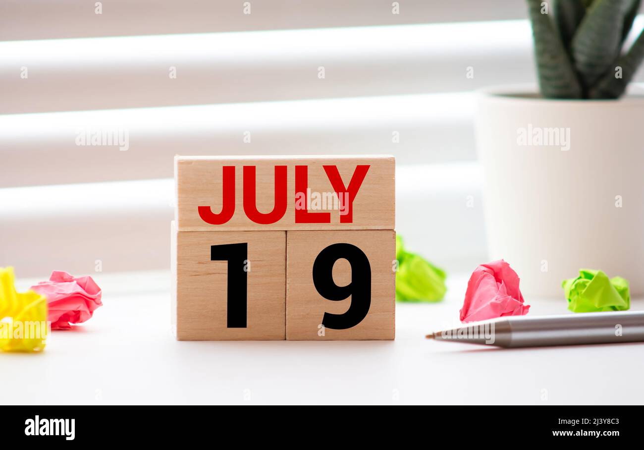 Juillet 19 - blocs de calendrier blancs sur table en bois sur fond bleu vintage. Banque D'Images