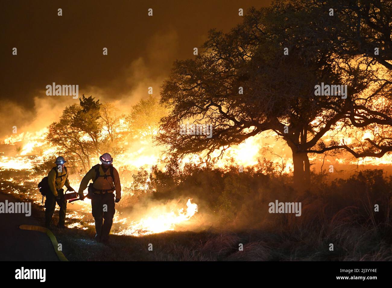 Texas State Forrest Service, Fredricksburg Task Force Strike équipe pompiers, marcher la ligne de crête d'un «burn-out» contrôlé qui a été commencé à gérer la zone d'un grand feu de forêt 9 avril 2022 à la base conjointe San Antonio - camp Bullis zone de démolition. JBSA-Camp Bullis comprend plus de 27 000 hectares de champs de tir, de zones d’entraînement et de terres sauvages du côté nord de San Antonio et est un lieu d’entraînement crucial pour les membres de la base conjointe de San Antonio. (É.-U. Photo de la Force aérienne par Brian Boisvert) Banque D'Images