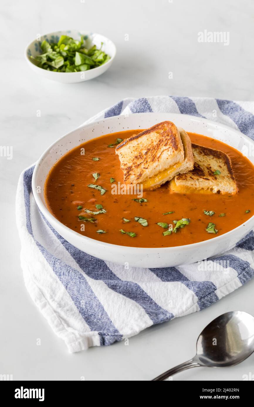 Un bol de soupe de tomates avec de petits carrés de sandwich au fromage grillé sur le dessus. Banque D'Images