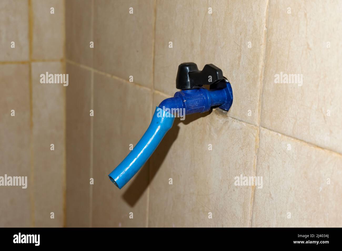 Le robinet d'eau bleu en plastique se trouve dans la salle de bains Banque D'Images