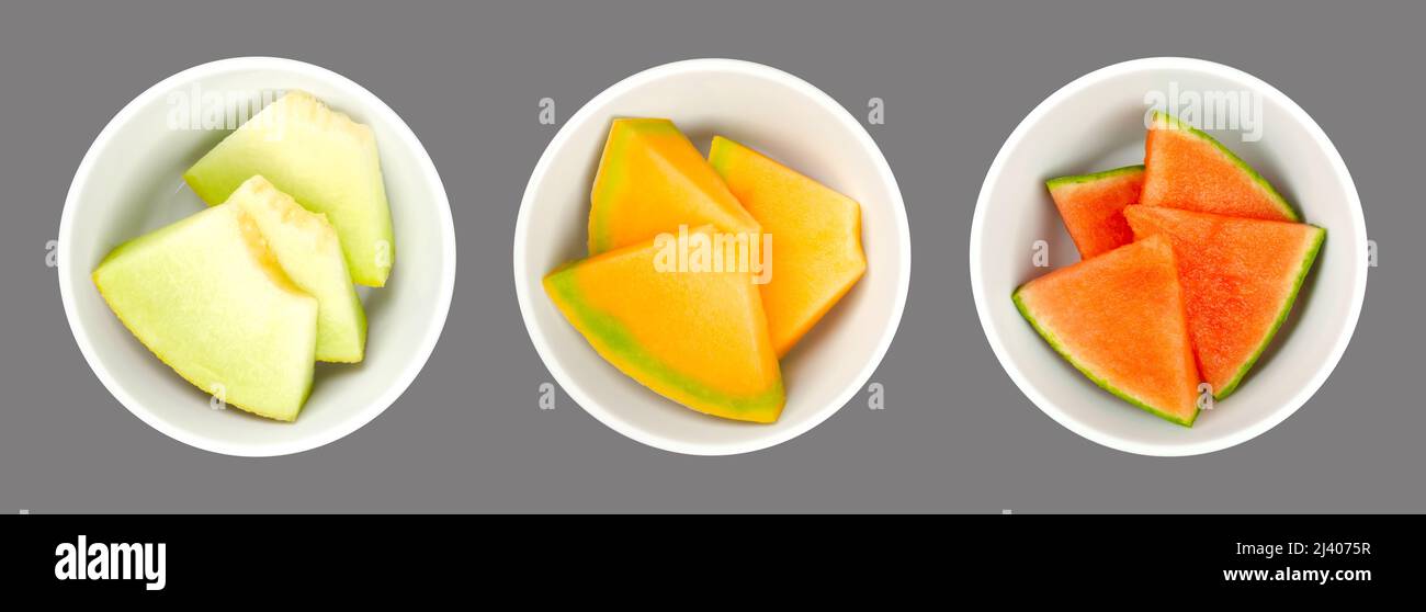 Tranches de melon, dans des bols blancs, sur fond gris. Galia, miel Cantaloup melon et pastèque. Pièces triangulaires fraîchement coupées. Banque D'Images