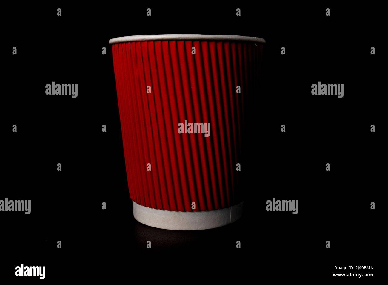 Tasse à café en papier rouge isolée sur fond noir. Banque D'Images
