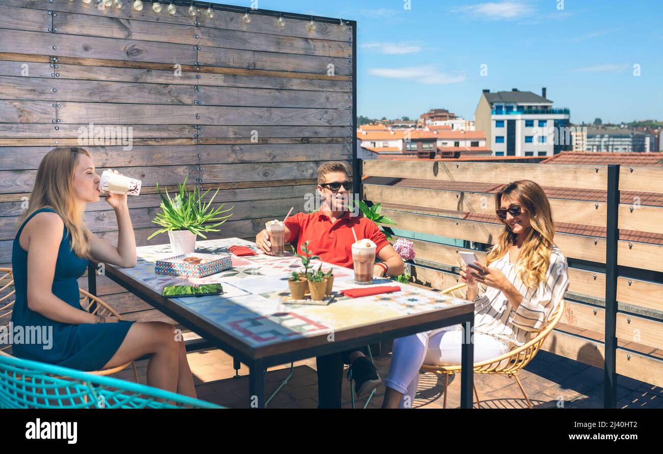 Personnes assises en train de boire un verre en terrasseen souriant et ...