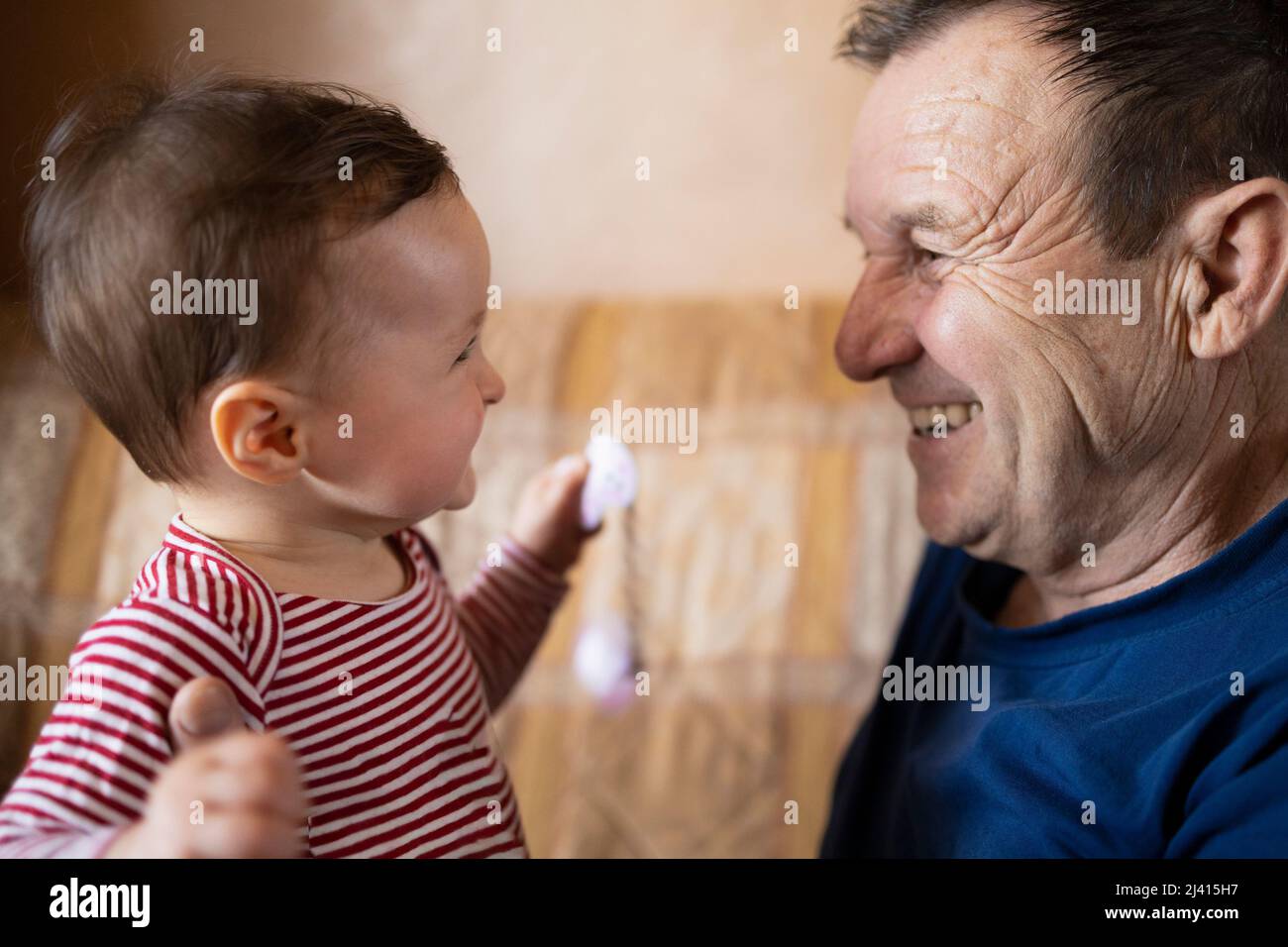 Bébé heureux et son grand-père souriant l'un à l'autre Banque D'Images
