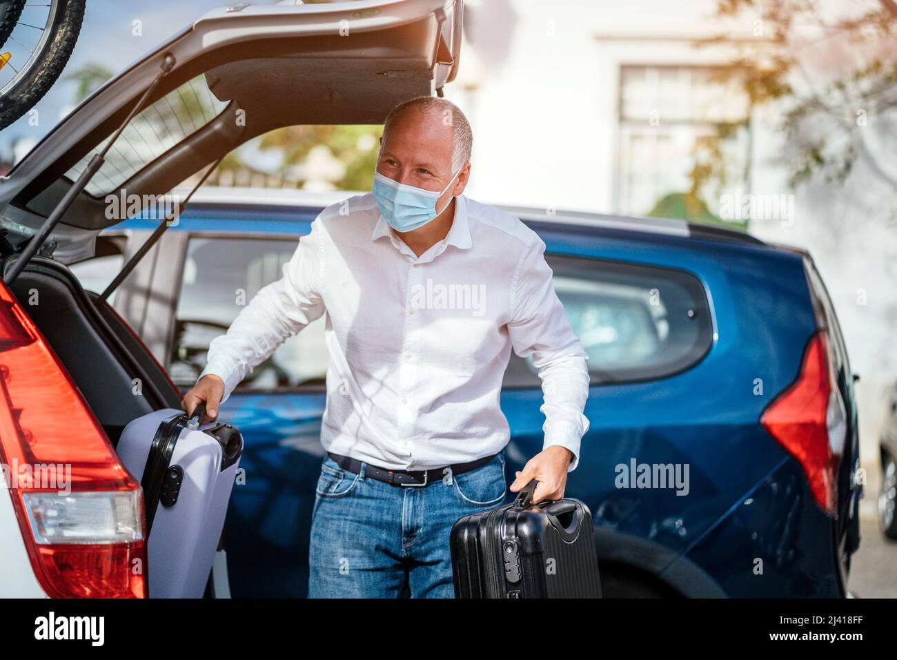 Un chauffeur de taxi ou Uber déchargeant les bagages du coffre de sa voiture Banque D'Images