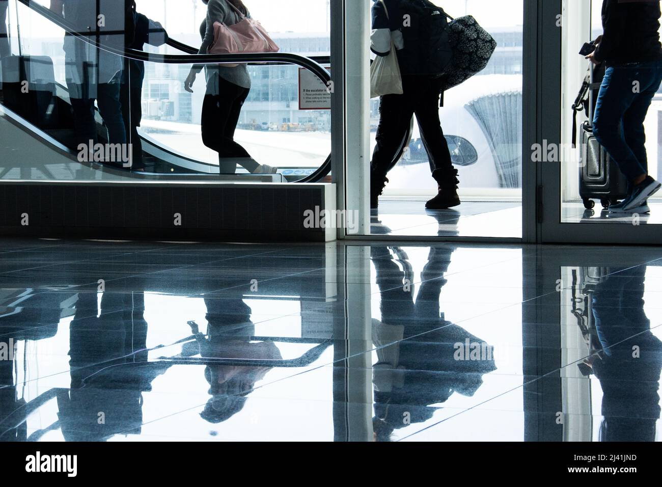 Les passagers à la porte de l'aéroport, devant l'avion, se rendre à l'escalier mécanique dans un bâtiment moderne à miroir et verre réfléchissant Banque D'Images