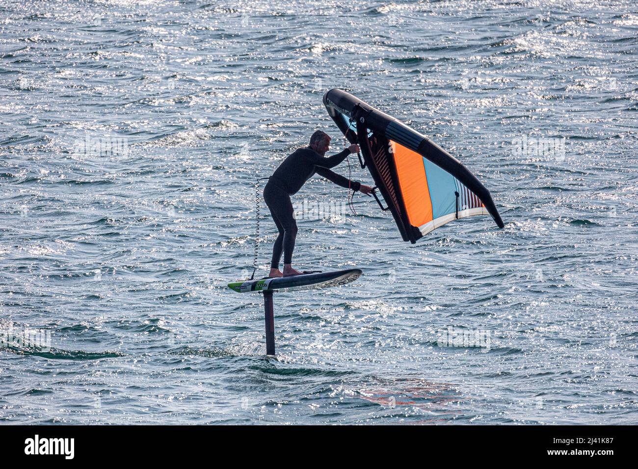 Marin Hydro déferlant à travers Mounts Bay, Cornwall sur une planche équipée d'un papier d'aluminium sur le point de s'écraser - photographié de l'espace public Banque D'Images