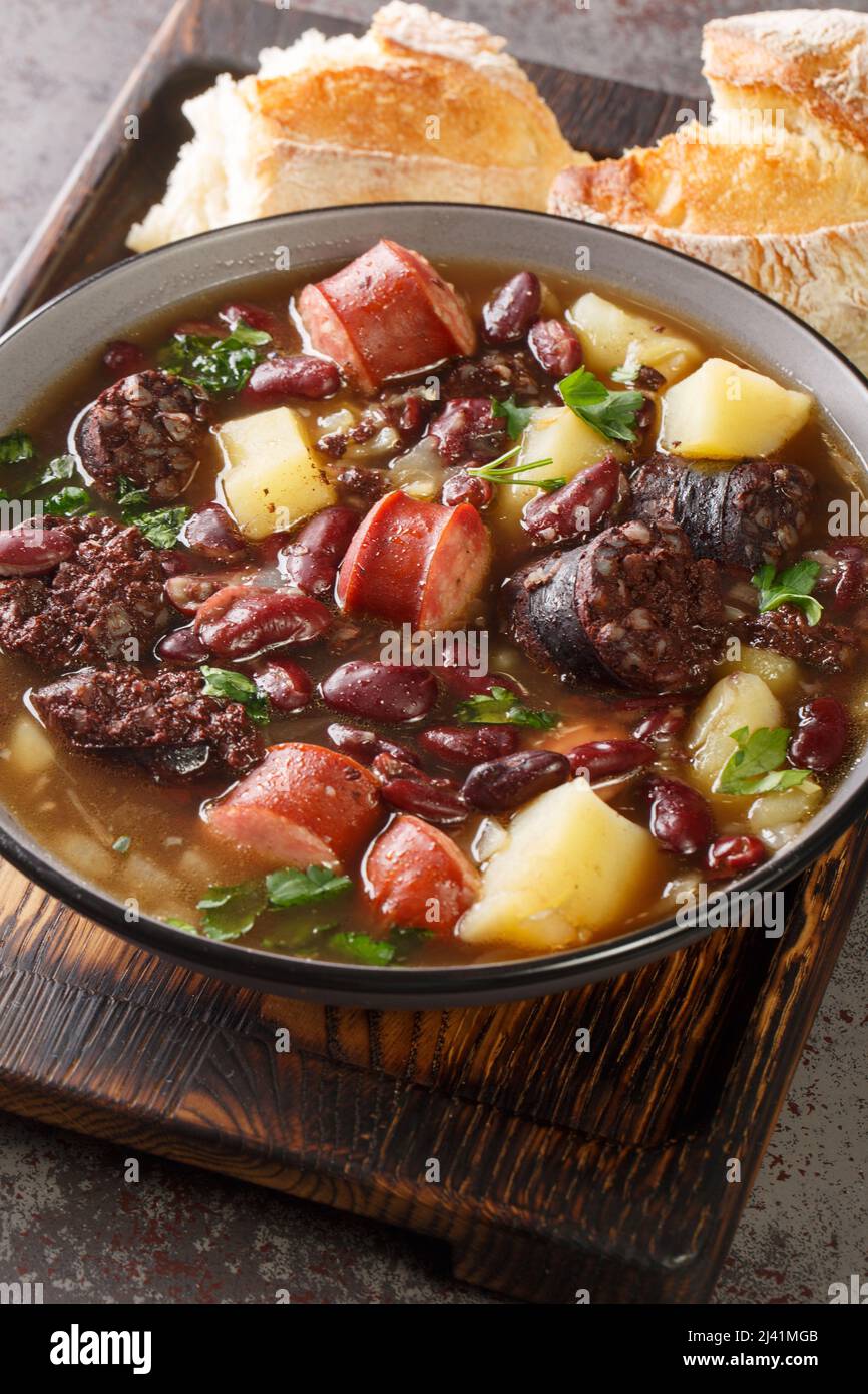 La recette traditionnelle de Sopa da Pedra combine des haricots rouges, des pommes de terre, de la viande séchée et des saucisses dans l'assiette sur la table. Verticale Banque D'Images