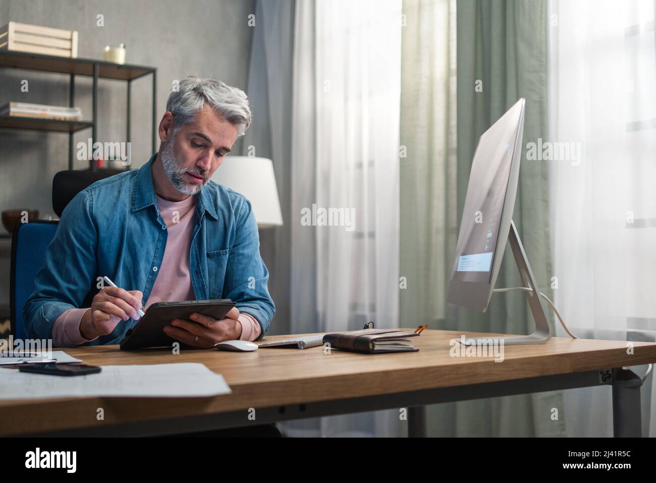 Homme mature architecte travaillant sur ordinateur au bureau à l'intérieur dans le bureau. Banque D'Images