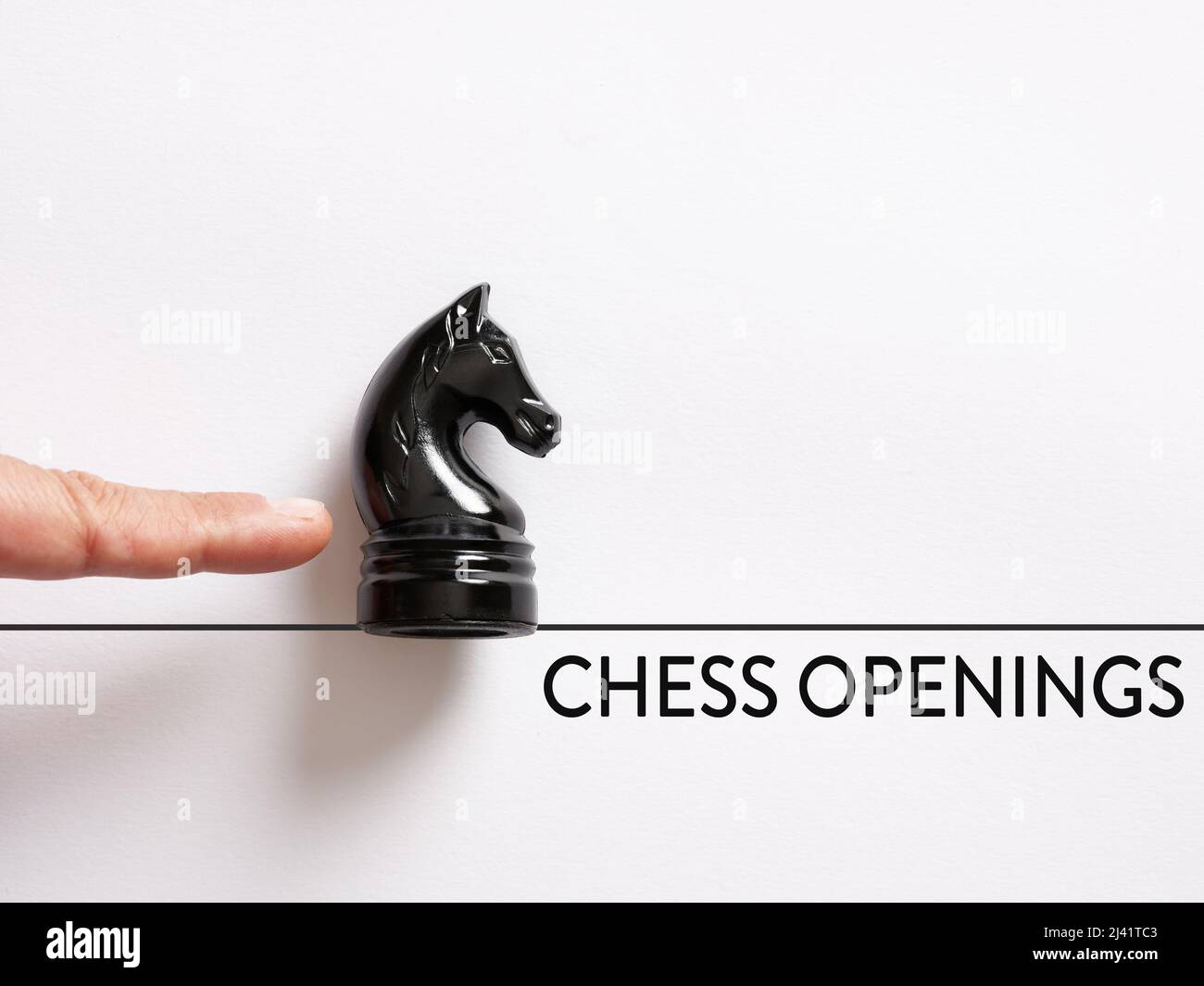 Le doigt pousse la pièce d'échecs de chevalier avec le message ouvertures d'échecs. Concept d'ouverture de jeu d'échecs. Banque D'Images