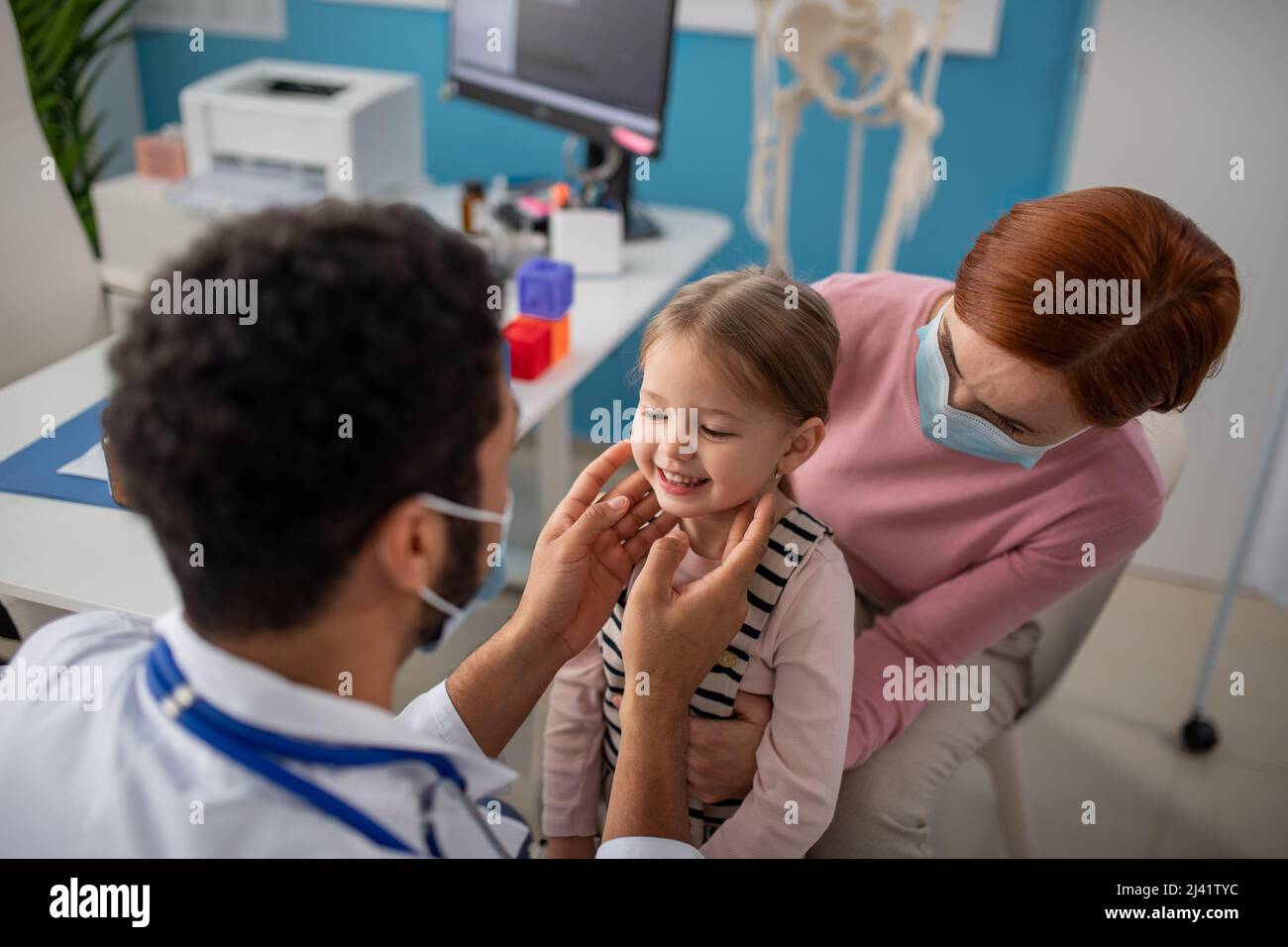 Jeune homme médecin vérifiant les ganglions lymphatiques de petite fille dans son bureau. Banque D'Images